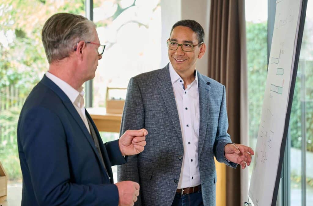 Dr. Eberhard Pantow im Gespräch mit einem Unternehmer am Whiteboard